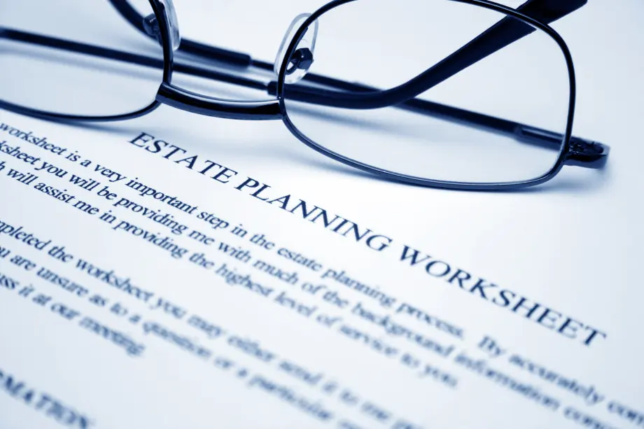 A pair of eyeglasses rests on top of a document titled "Estate Planning Worksheet" with text visible below the heading.