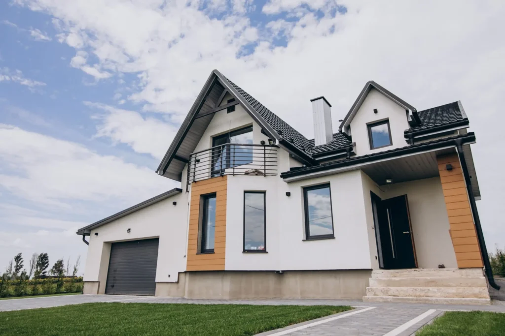 Modern two-story house with a sloped roof, large windows, balcony, attached garage, and front entrance with steps. Perfect for those mindful of tenant rights during a property sale, set against a partly cloudy sky.